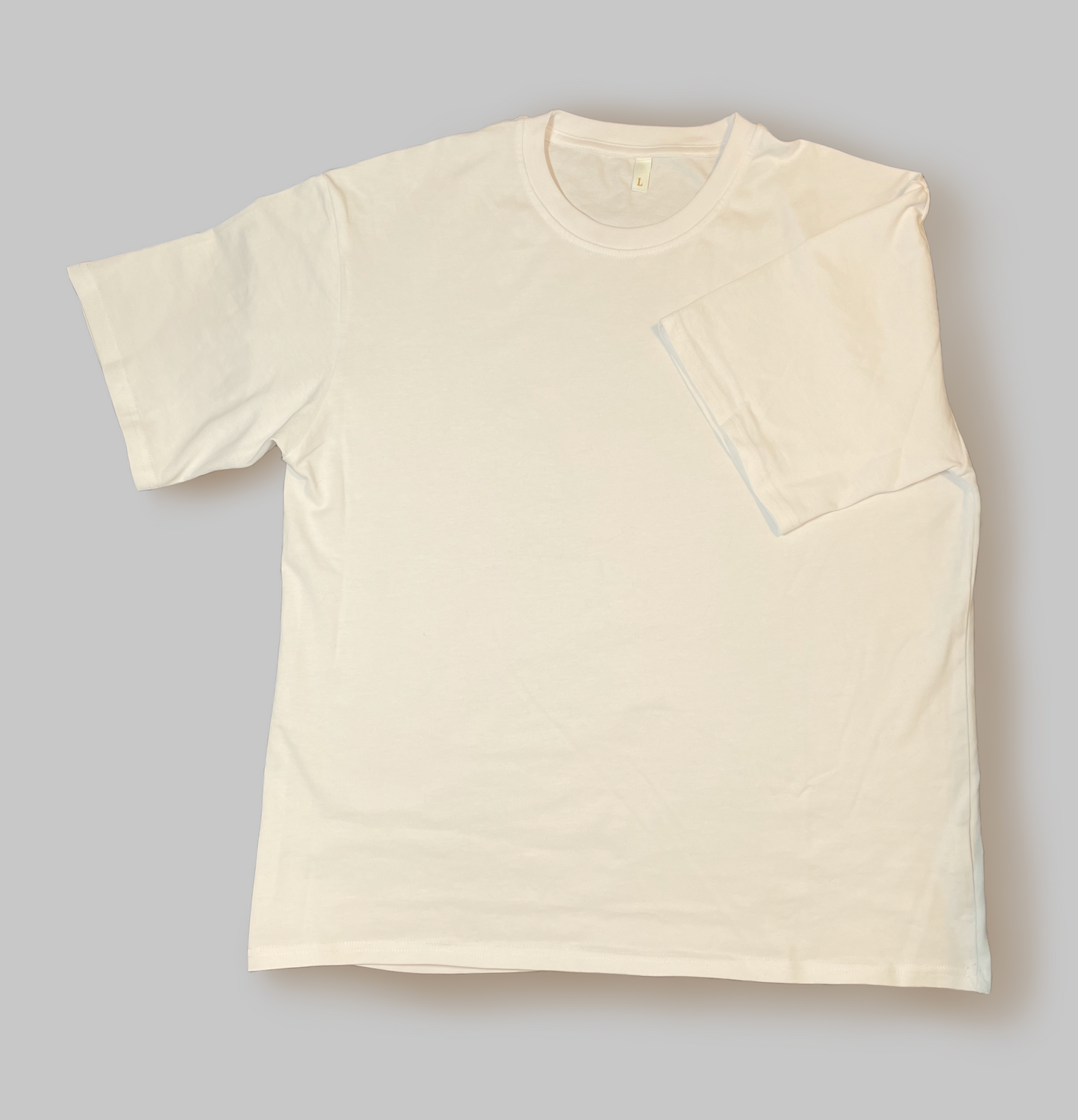 A white cotton T Shirt laid out flat with a sleeve folded into the middle of the shirt